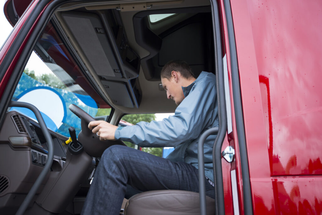 Truck driver at the steering wheel of a semi-truck using a tablet